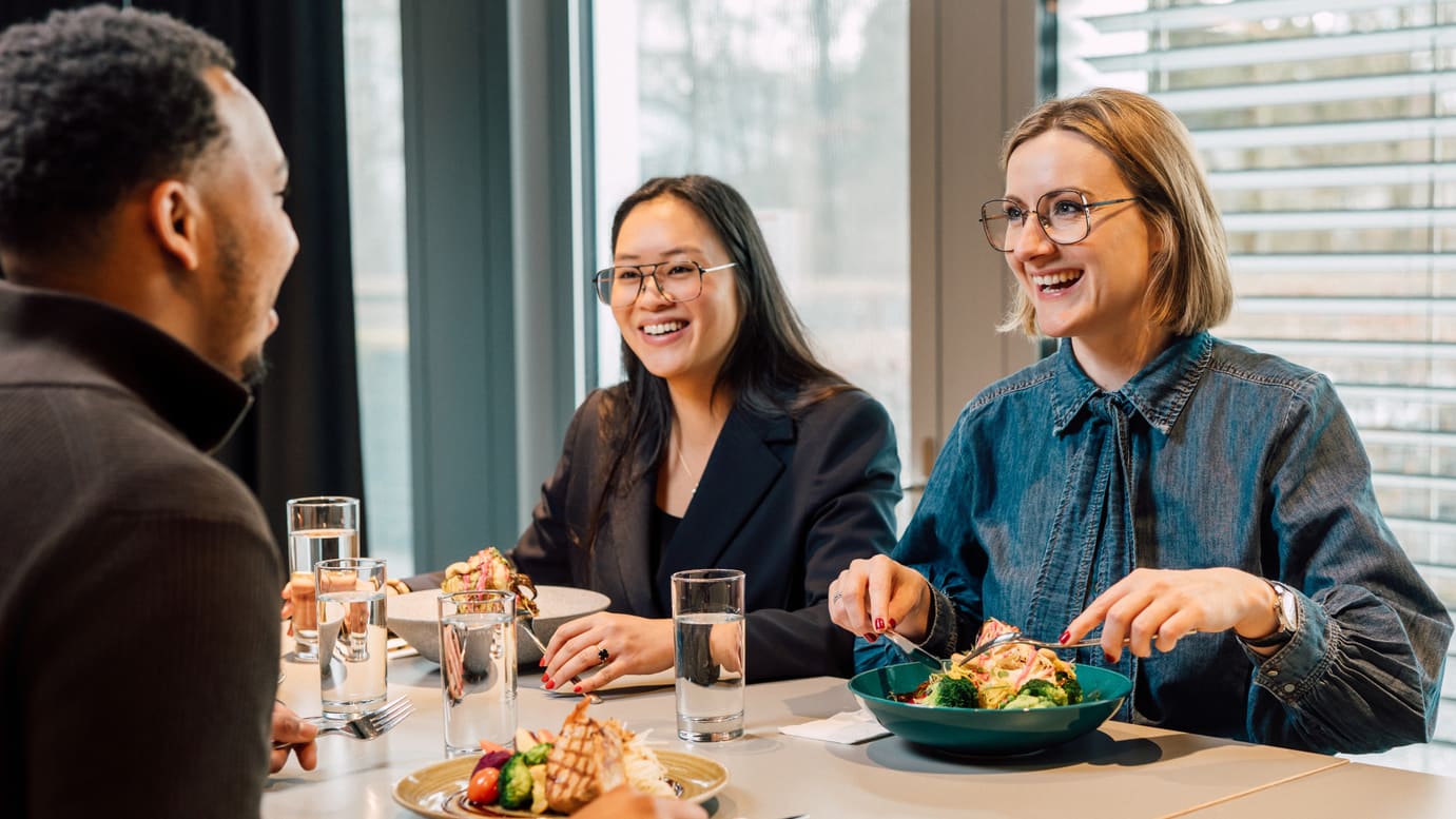 Drei Personen beim Mittagessen und Unterhalten in einem Restaurant.