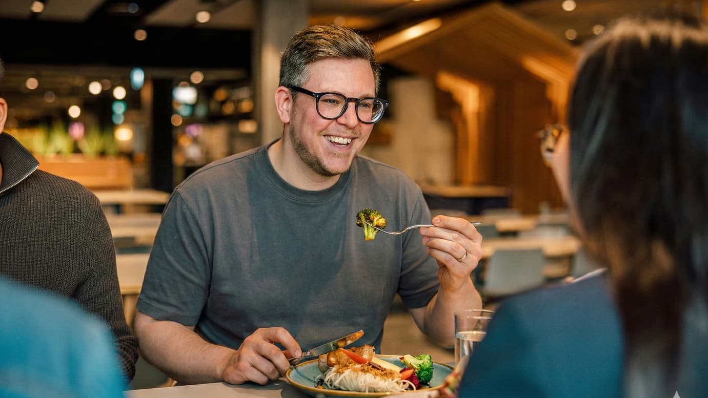 Mann lächelnd beim Essen in einem Restaurant.