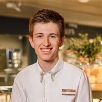 Junger Mann in weissem Hemd lächelnd in einem Geschäft.