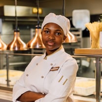 Koch in weisser Uniform in einer Restaurantküche.