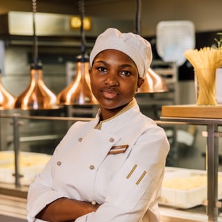 Koch in weisser Uniform in einer Restaurantküche.