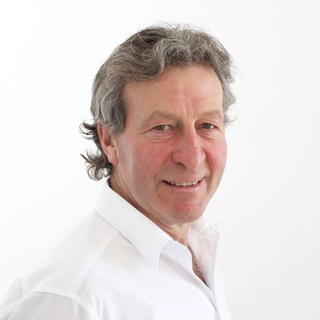 Mann in weissem Hemd vor weissem Hintergrund, lächelnd.",