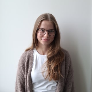 Lächelnde Frau mit Brille vor weissem Hintergrund.