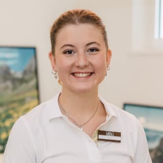 Junge Frau in einem weissen Polohemd lächelt.