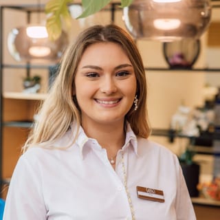 Porträt einer lächelnden Frau in einem weissen Hemd.