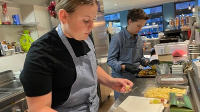 Zwei junge Köche bereiten Speisen in einer Küche zu.