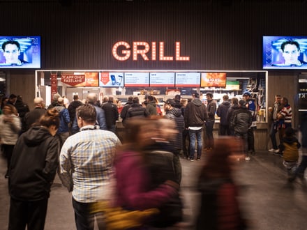 Belebte Szene vor einer Essenstation im Stadion an einem Eishockey Match in der Swiss Life Arena in Altstetten Zürich, wo die Fans auf ih Essen warten.