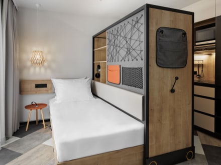 Modernes Hotelzimmer mit kleinem Bett und Holzdekor.