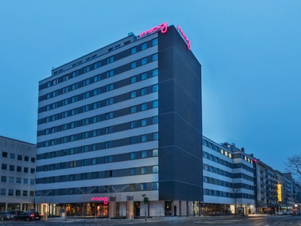 Modernes Hochhaus bei Dämmerung mit Leuchtreklame auf dem Dach.