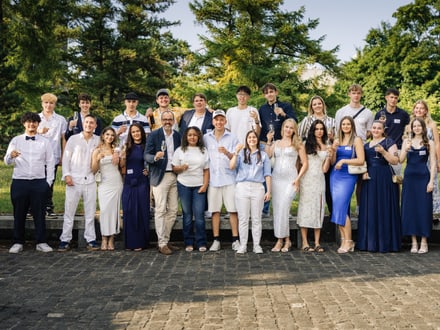 Gruppe junger Menschen im Freien, Bäume im Hintergrund.