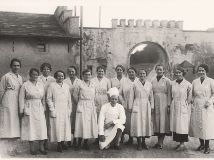 Historisches Bild von einem Küchenteam auf einem Hof als Gruppe fotografiert.