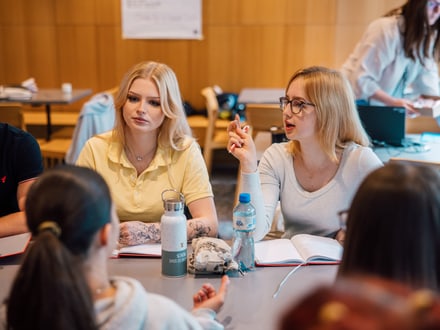 Gruppe von Studenten diskutiert im Klassenzimmer.