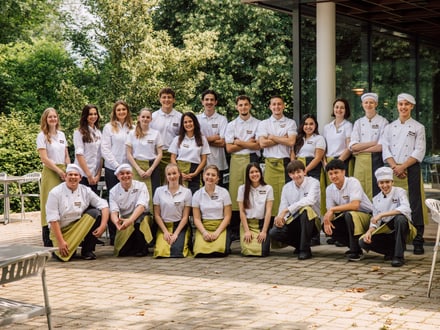 Gruppenfoto von Restaurantpersonal vor einem Gebäude im Freien.