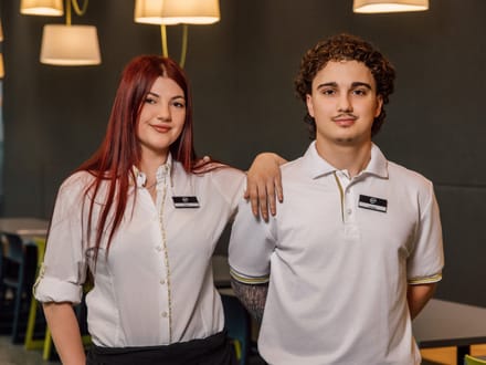 Zwei Personen in weisser Kleidung und Schürzen stehen in einem modernen Restaurant.
