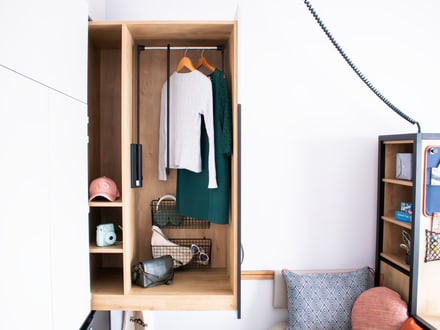 Modern gestalteter Kleiderschrank mit Kleidung und Accessoires in einem minimalistischen Zimmer.