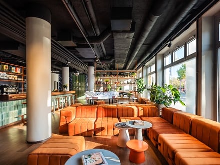 Salon moderne avec canapés orange et grandes fenêtres.