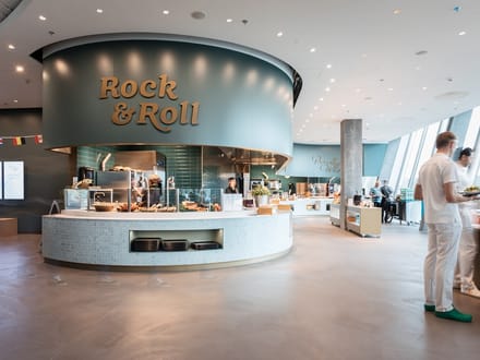 Moderne Cafeteria mit runden Theken und Personen in weisser Kleidung.