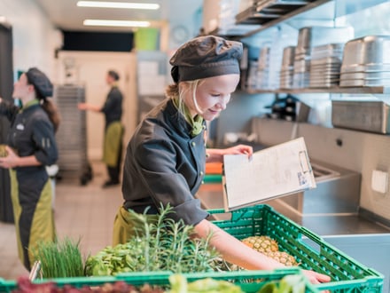 Lernende Köchin prüft Lebensmittel in der Restaurantküche.