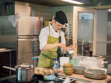 Koch in einer Restaurantküche bei der Zubereitung von Speisen.