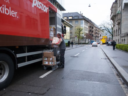 Lieferwagen mit Person beim Beladen an einer städtischen Strasse.