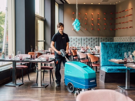 Person reinigt ein Restaurant mit einer Bodenreinigungsmaschine.