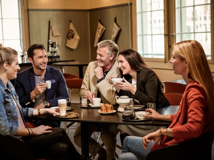 Menschen, die in einem Café Kaffee trinken und lachen.