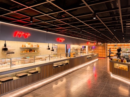 Moderne Kantine mit Buffet und Neonlichtern.