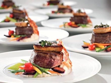 Mehrere Teller mit Gourmetgerichten, darunter Fleisch und Gemüse.