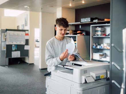 Junger Mann benutzt einen Kopierer im Büro.