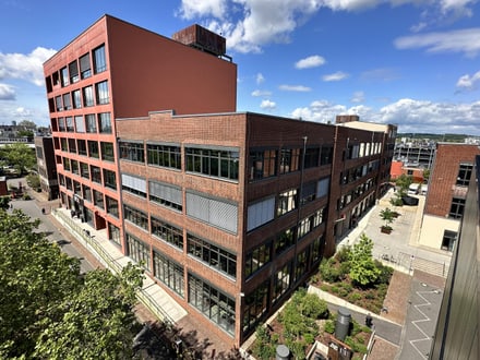 Luftaufnahme eines modernen Bürogebäudes in städtischer Umgebung bei Tageslicht.