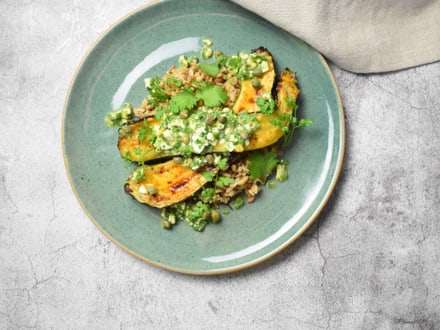 Gebratene Zucchini mit Erbsen und Kräutern auf grünem Teller.