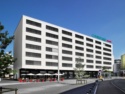 Aussenansicht des Hotels Courtyard by Marriott in Zürich, helles Gebäude mit vielen Fenstern an einer Strasse.