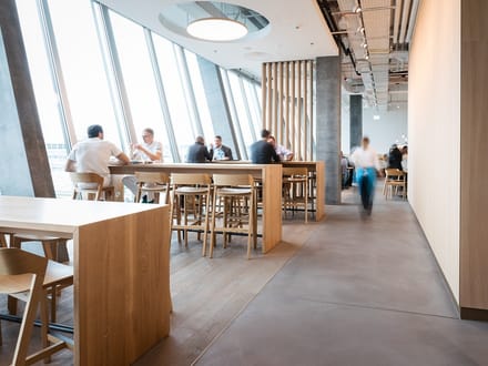 Innenansicht eines modernen Cafés mit Menschen an Tischen.