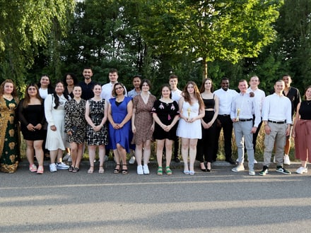 Gruppenfoto von zwanzig Personen in sommerlicher Kleidung im Freien.