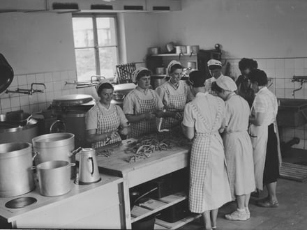 Historisches Bild von Frauen in der Küche, die Bohnen schneiden.