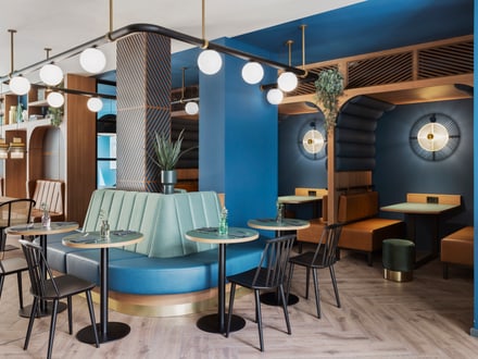 Modernes Restaurantinterieur mit blauen Wänden und runden Tischen.