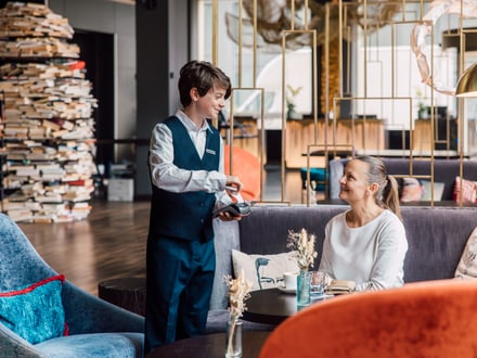 Kellner bringt einer Frau in einem Café etwas zu trinken.