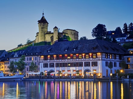 Aussenansicht des Güterhofs Schaffhausendirekt am Rhein in der Dämmerung schön beleuchtet und im Hintergrund der Munot.