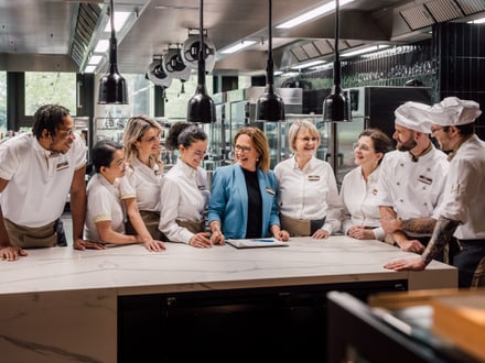 Team von Köchen und Angestellten versammelt sich in der modernen Küche.