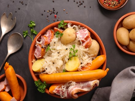 Sauerkraut mit Würstchen, Kartoffeln und Schinken in einer Schüssel.