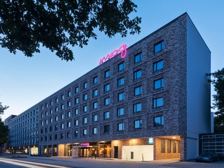 Modernes Hotelgebäude bei Dämmerung mit erleuchtetem Schild.