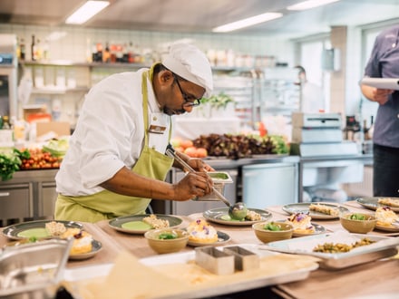 Chefkoch verfeinert Teller in einer professionellen Küche.