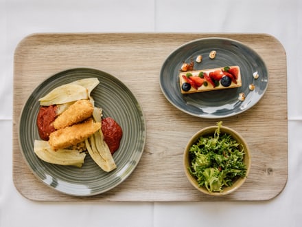 Holztablett mit frittierten Speisen, Kuchen und Salat.