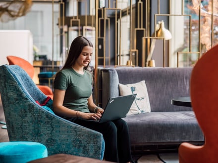 Frau mit Laptop in modernem Wohnzimmer.