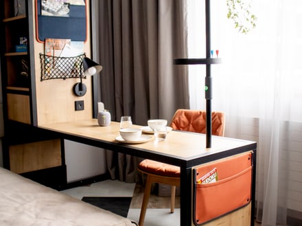 Modern gestalteter Arbeitsplatz mit integriertem Regal und Schreibtisch, dekorativem Lampenpfosten und Schlafsofa.