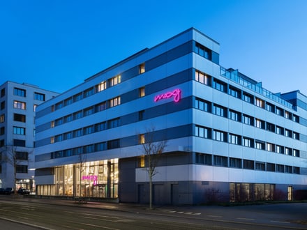 Modernes Hotelgebäude mit leuchtendem rosa Schild am Abend.