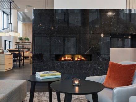 Moderne Hotellobby mit schwarzer Marmorwand und Kamin.