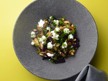 Grauer Teller mit Gericht auf gelbem Hintergrund.