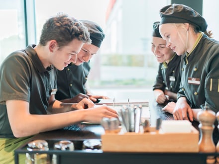 Gruppenbild von vier Lernenden an einem Tisch