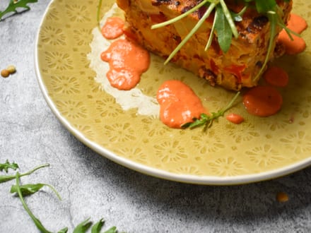 Gericht mit gegrilltem Fisch, Salat und roter Sosse auf verziertem Teller.